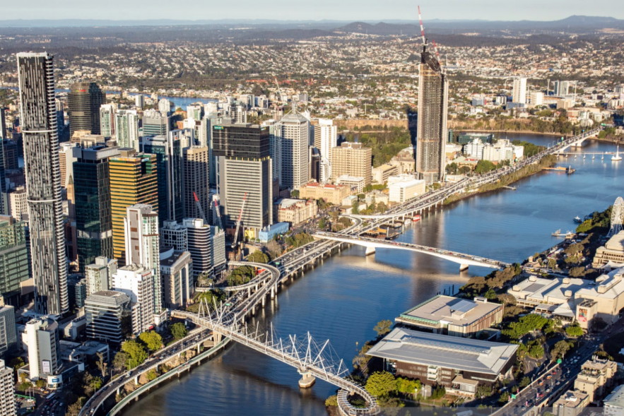 A view of Brisbane city from a helicopter. The Brisbane River can be seen winding its way through the heart of the city with several of the bridges that connect the north and south sides of the city.